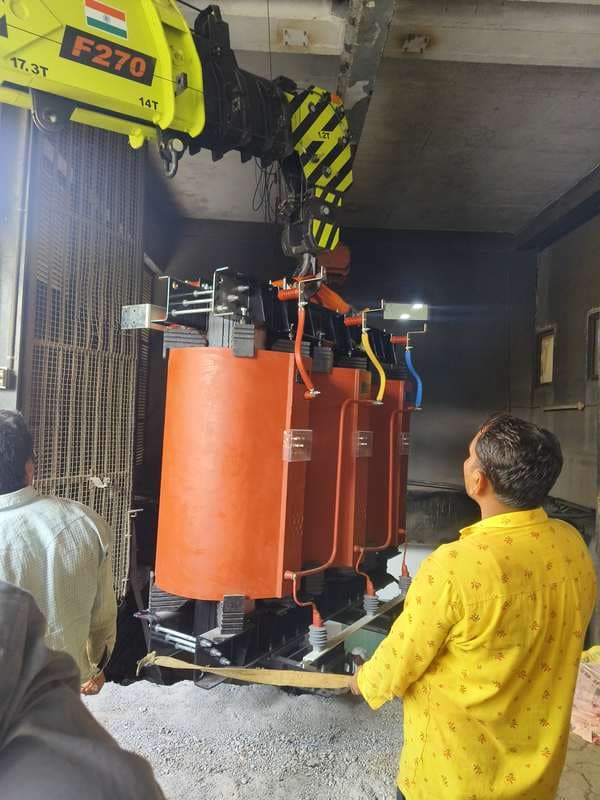 Cast-resin transformer being lowered into a basement level by a truck-mounted crane.